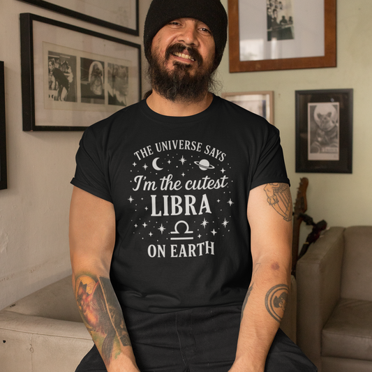 Man wearing a black T-shirt with the text “The Universe Says I’m the Cutest Libra on Earth” in a fun astrology design with stars, moon and planet graphics.