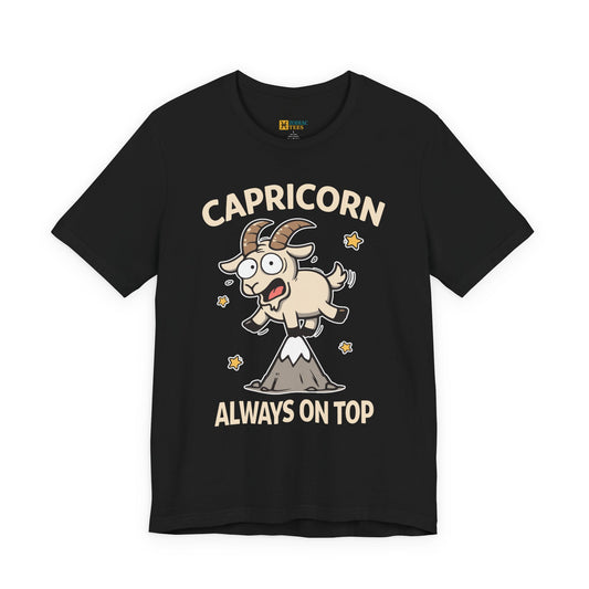 Black Capricorn ‘Always On Top’ T-shirt with a cartoon goat illustration standing on a mountain peak, shown as a flat product image.
