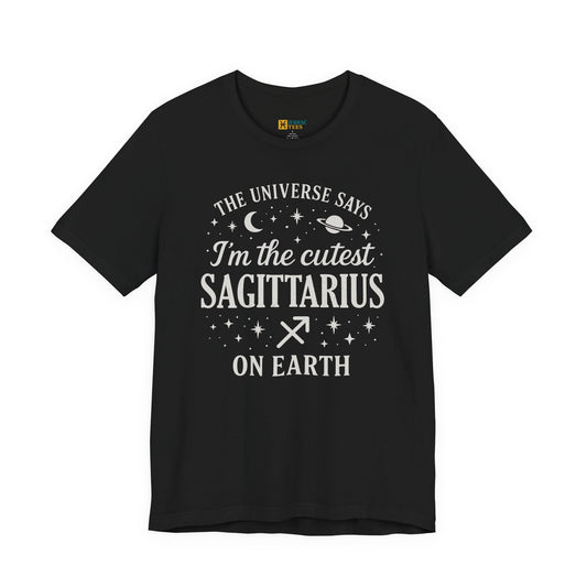 A black T-shirt featuring a white Sagittarius zodiac typography design that reads “The Universe Says I’m the Cutest Sagittarius on Earth,” with stars, a crescent moon, a planet and the Sagittarius zodiac symbol.
