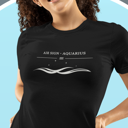 A young woman wearing a black T-shirt with a white “Air Sign · Aquarius” design featuring a minimalist wave graphic. Soft blue circular background behind her.