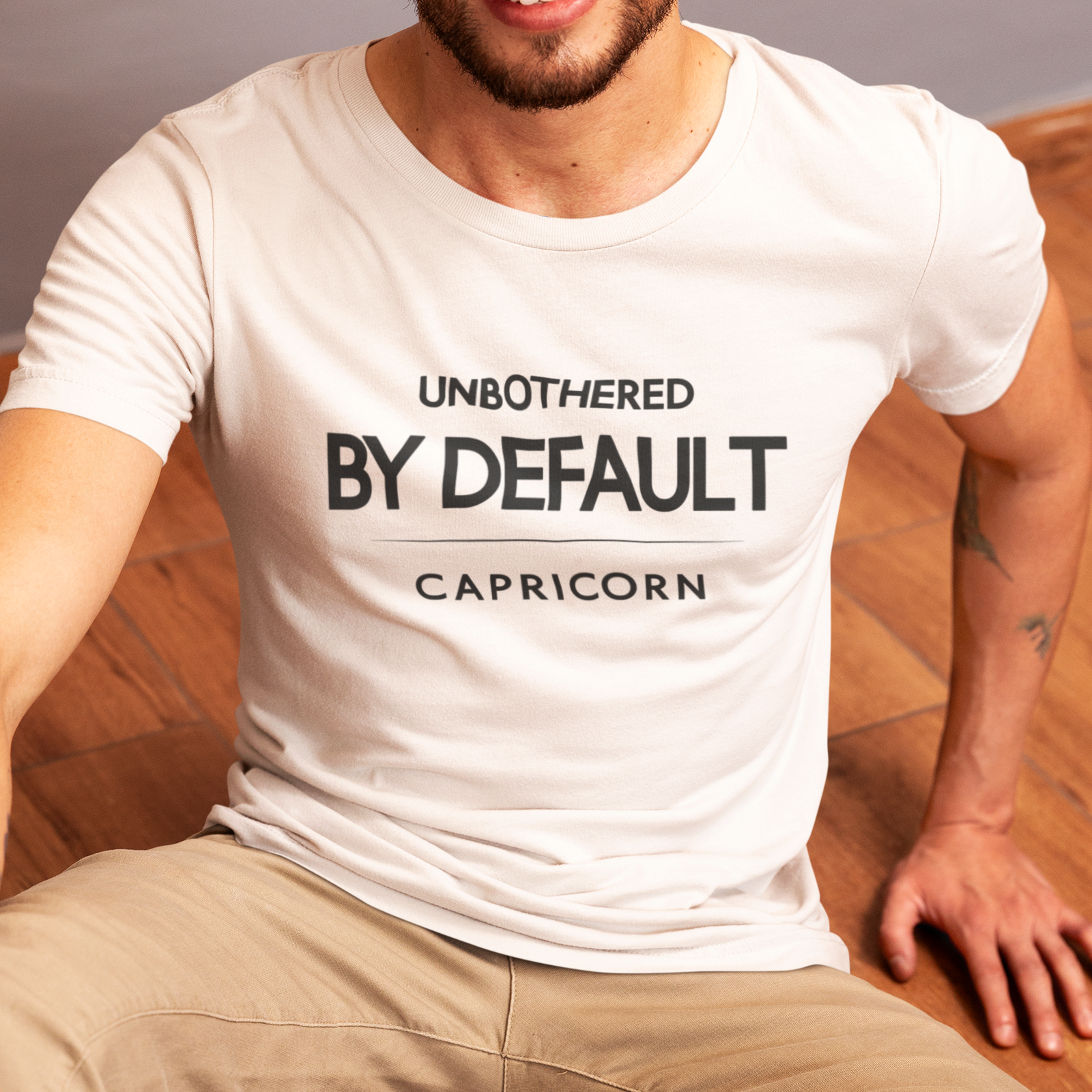 Model wearing Capricorn zodiac t-shirt with “Unbothered by Default” typography quote design