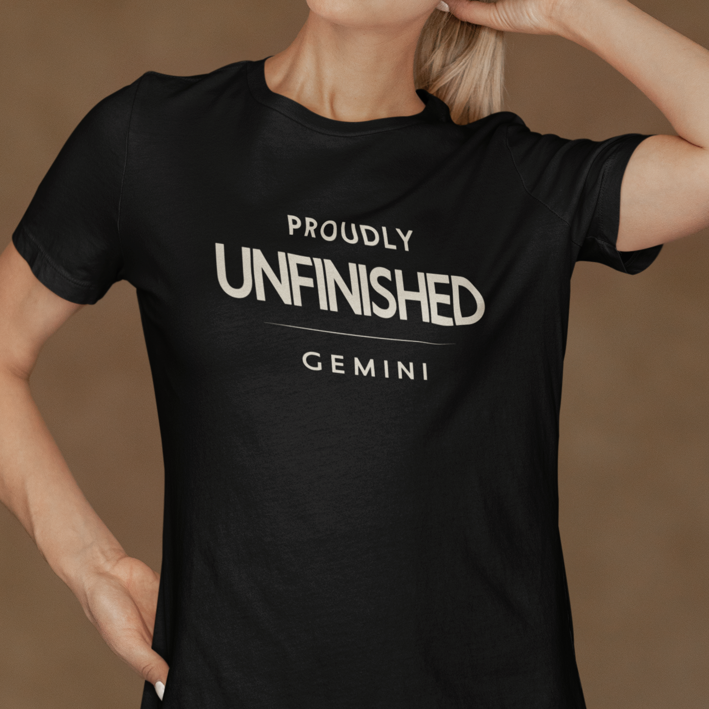 Model wearing Gemini zodiac t-shirt with bold “Proudly Unfinished” typography quote design