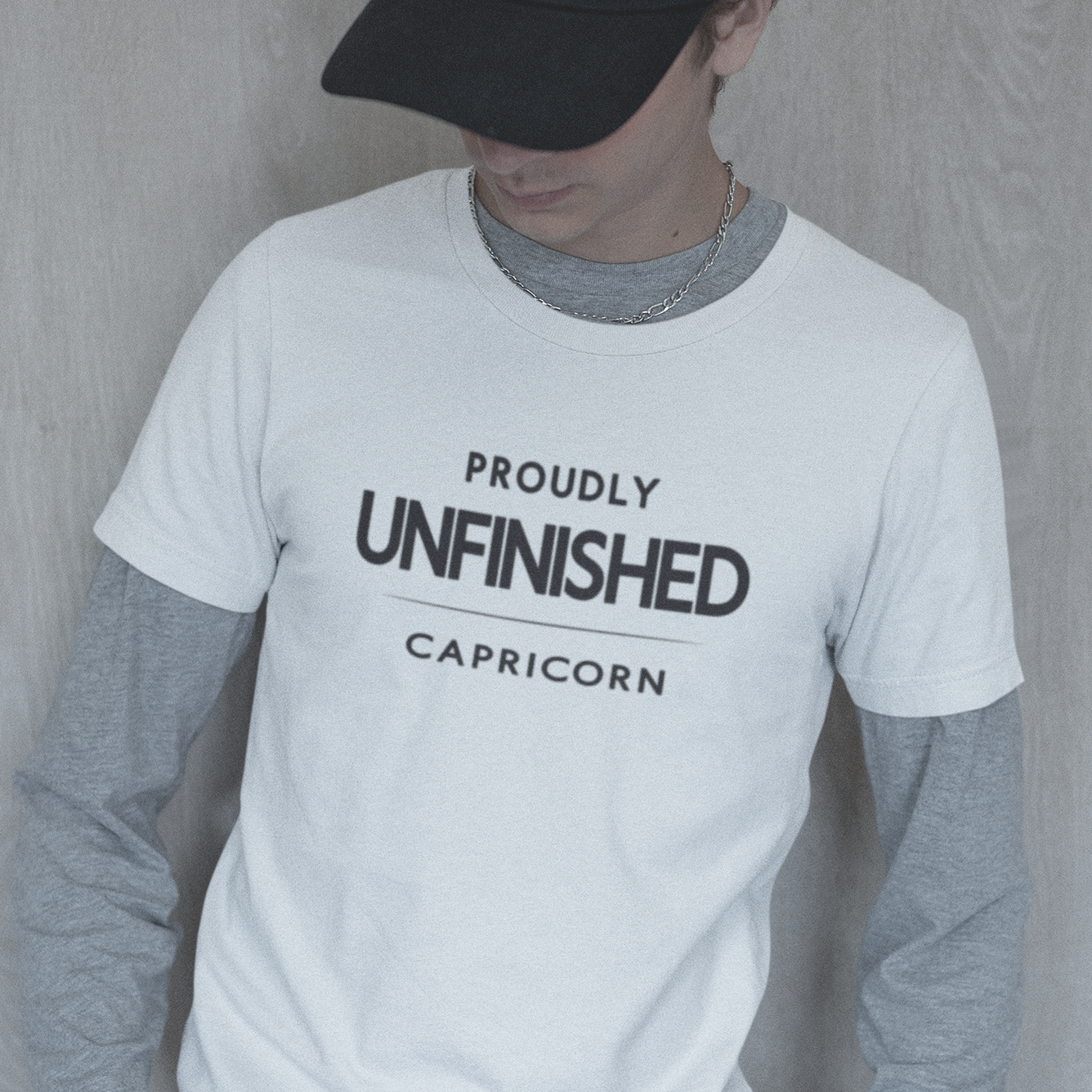 Model wearing Capricorn zodiac t-shirt with “Proudly Unfinished” typography quote design