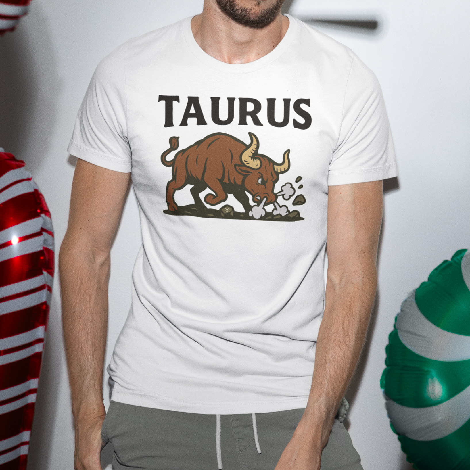 Man wearing a white Taurus T-shirt with a charging bull graphic, standing next to large candy cane decorations.
