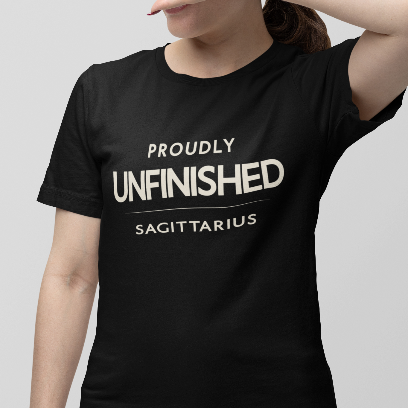 Model wearing Sagittarius zodiac t-shirt with “Proudly Unfinished” typography quote design