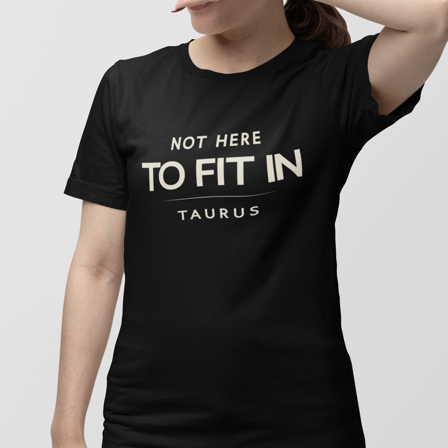 Model wearing Taurus zodiac t-shirt with “Not Here to Fit In” typography quote design