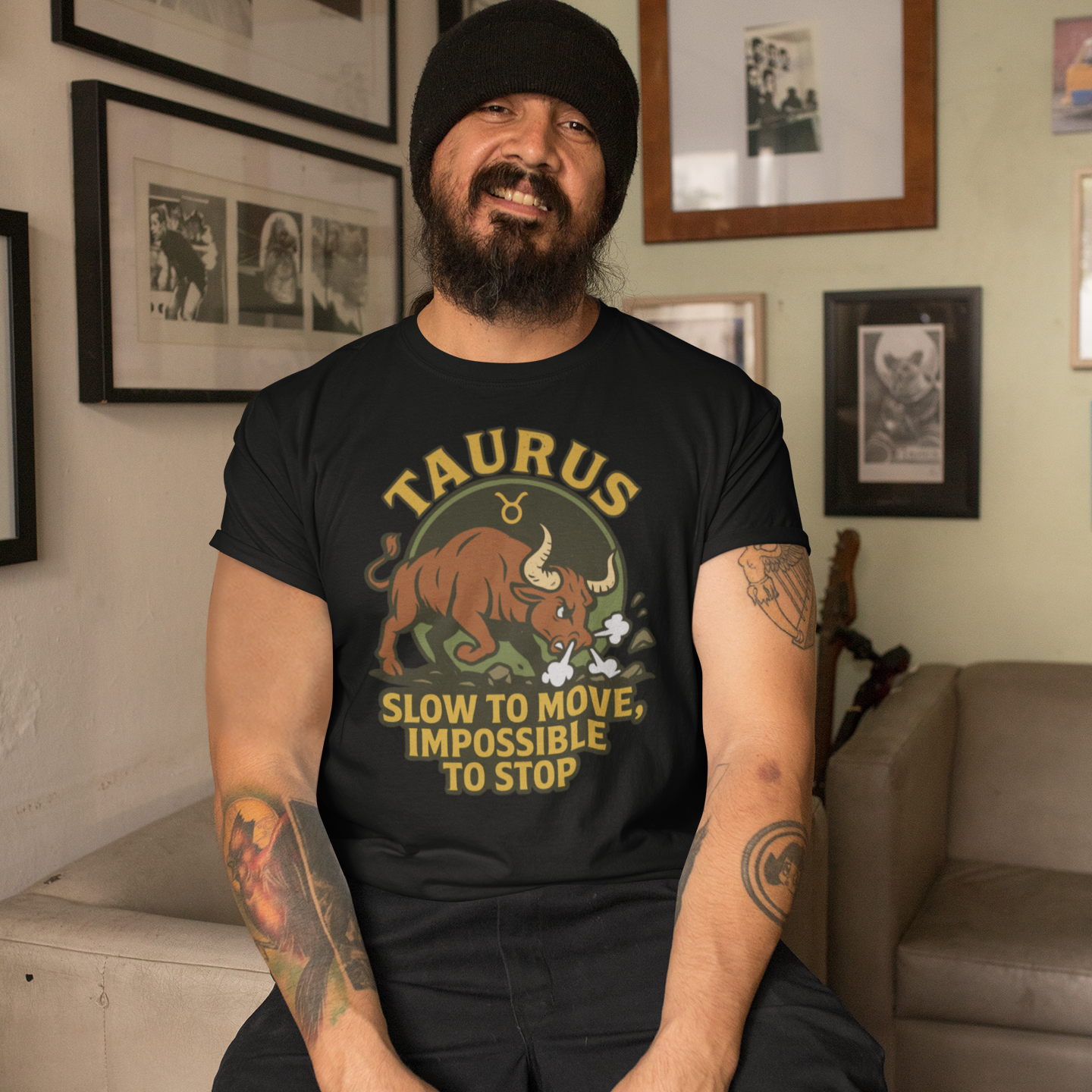 Man wearing a black Taurus Slow to Move T-Shirt with charging bull design while sitting in a cozy room