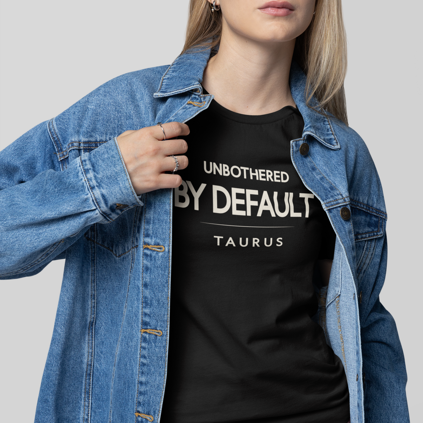 Model wearing Taurus zodiac t-shirt with “Unbothered by Default” typography quote