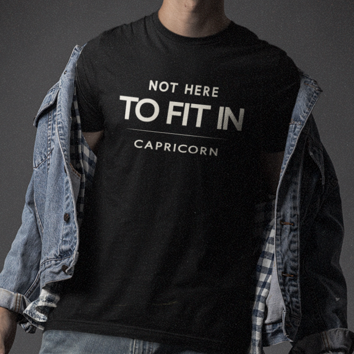 Model wearing Capricorn zodiac t-shirt with “Not Here to Fit In” typography quote design