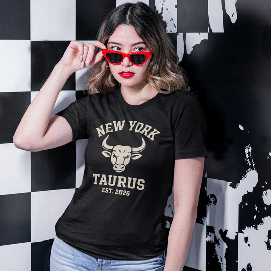 Woman wearing a black Taurus Varsity T-Shirt with bold bull emblem, standing in front of a graffiti wall