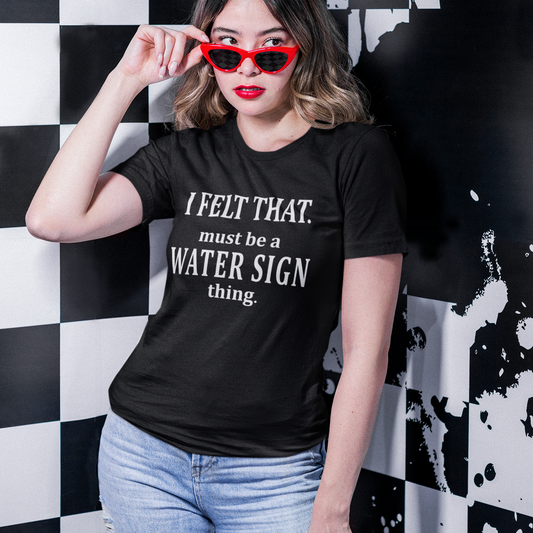 Woman wearing a black water sign astrology t-shirt with the phrase “I Felt That. Must Be a Water Sign Thing” in a casual lifestyle setting.