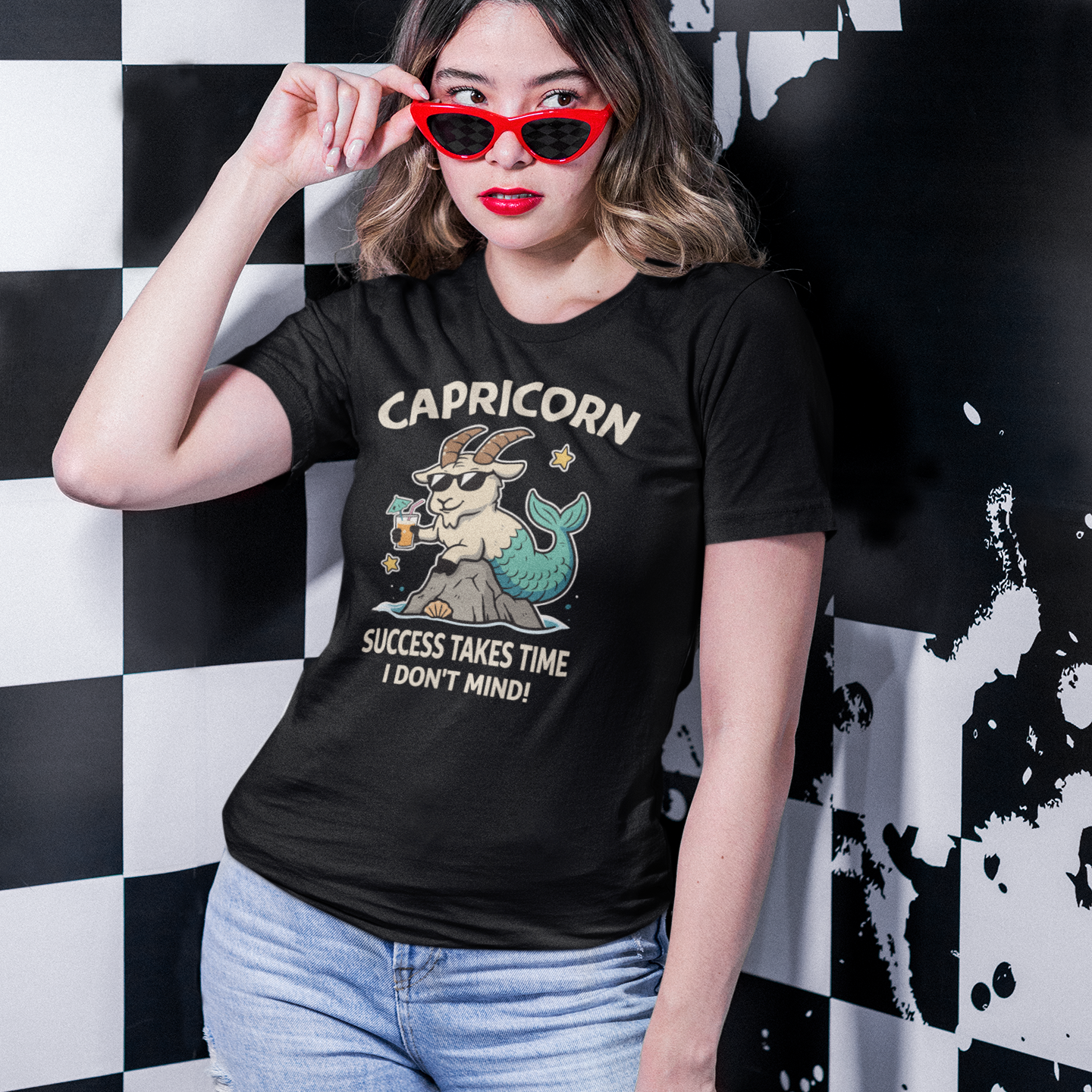 Woman wearing a black Capricorn zodiac T-shirt featuring a relaxed cartoon sea-goat design with the text “Success Takes Time, I Don’t Mind” in a lifestyle setting.